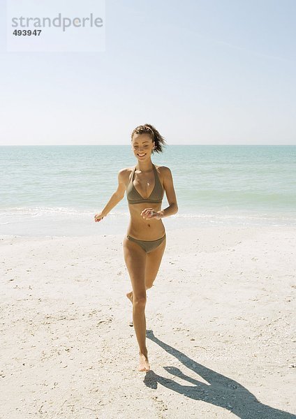 Junge Frau beim Laufen am Strand