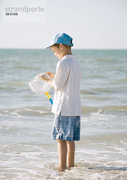 Junge im Meer stehend mit Fischernetz