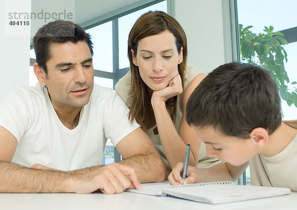 Eltern helfen dem Sohn bei den Hausaufgaben