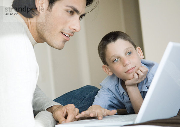Mann und Junge benutzen gemeinsam einen Laptop
