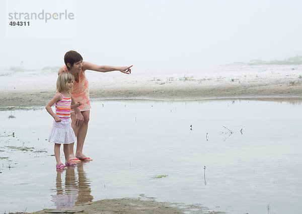 Mutter und Tochter am Strand  Mutter zeigt auf Distanz