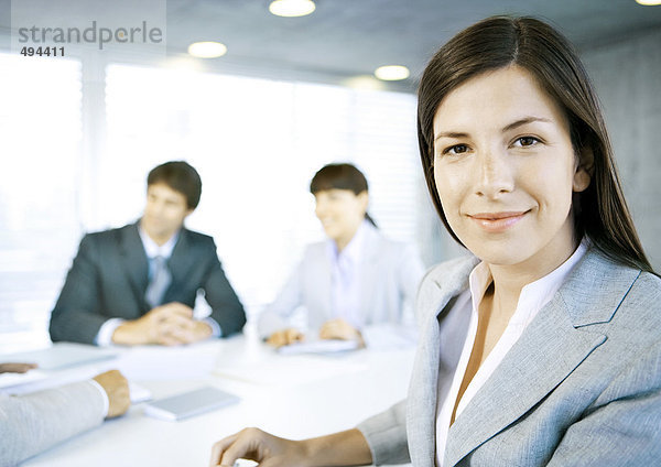 Geschäftsfrau lächelt vor der Kamera  Treffen im Hintergrund