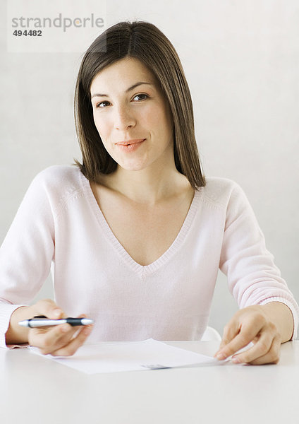 Frau sitzend mit Stift und Dokument