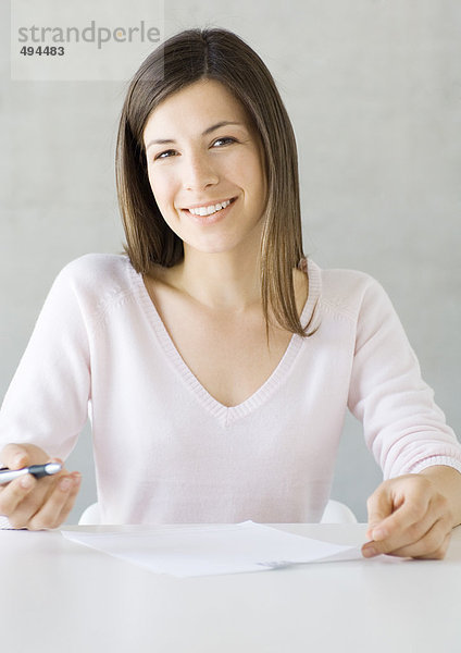 Frau sitzend mit Stift und Dokument