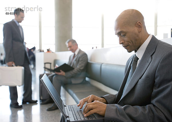 Geschäftsmann mit Laptop im Loungebereich des Flughafens