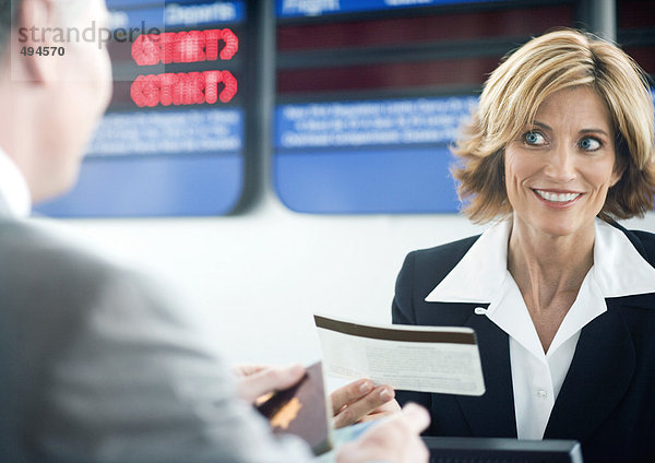 Flugbegleiter bei der Abgabe des Passagiertickets am Check-in-Schalter