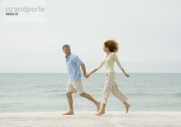 Erwachsene Paare  die am Strand laufen