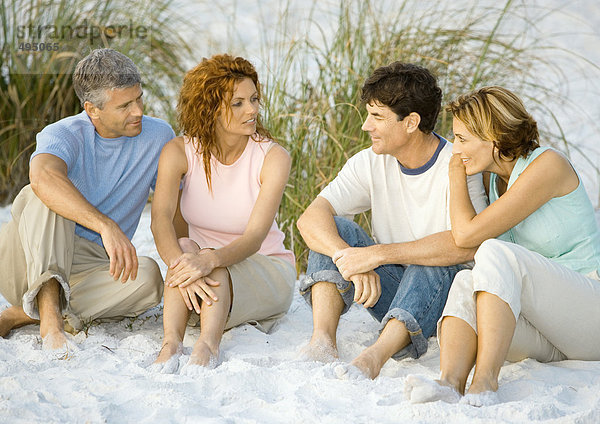 Zwei reife Paare  die am Strand sitzen und reden