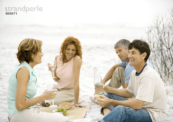 Zwei reife Paare beim Picknick am Strand