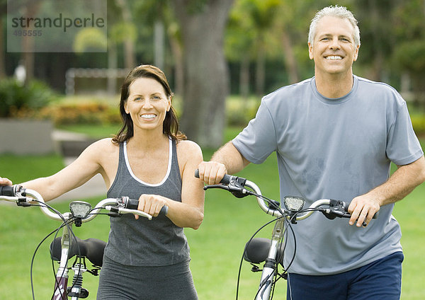 Erwachsenes Paar steht neben Fahrrädern  lächelnd