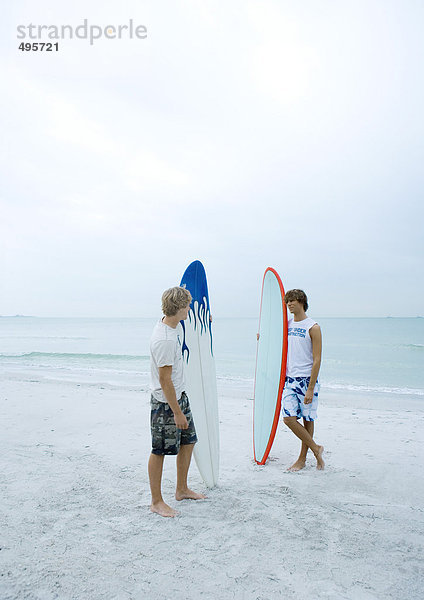 Zwei Surfer stehen am Strand