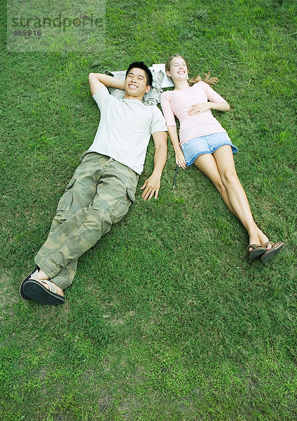 Junges Paar im Gras liegend mit auf Büchern ruhenden Köpfen  Hochwinkelansicht