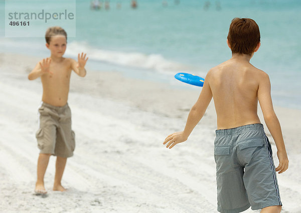 Jungs spielen Frisbee am Strand