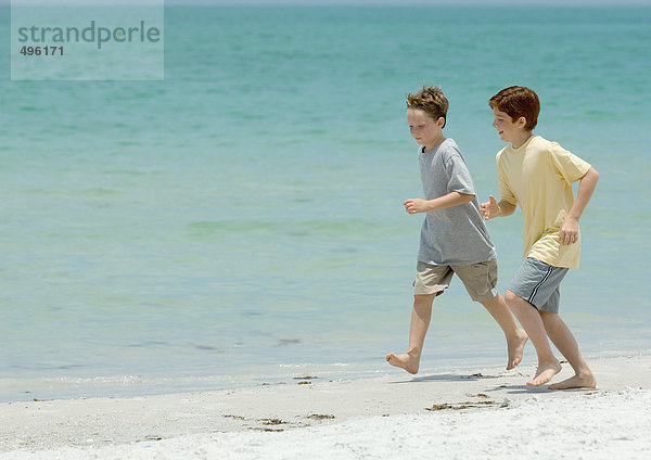 Jungen  die neben dem Strand surfen.