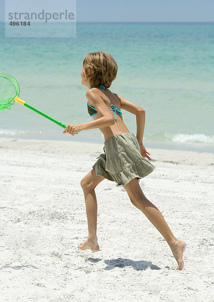 Mädchen beim Laufen mit Fischernetz am Strand