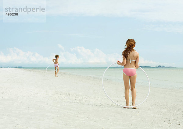 Mädchen spielen mit Plastikreifen am Strand