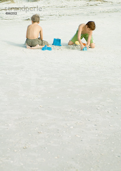 Jungen spielen im Sand am Strand