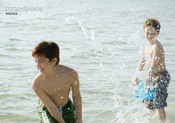 Jungen planschen im Meer mit Eimern