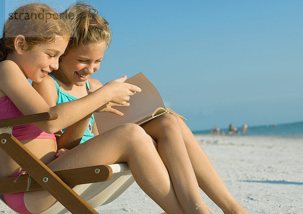 Mädchen beim gemeinsamen Lesen am Strand