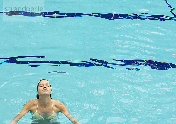 Frau im Pool stehend  Kopf hinten und Augen geschlossen  Frontansicht