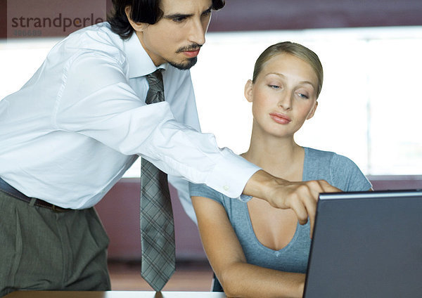 Geschäftsmann hilft Geschäftsfrau mit Laptop