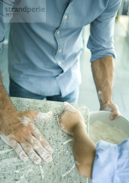 Mädchen und Vater wischen Mehl auf der Theke in die Rührschüssel  Schnittansicht