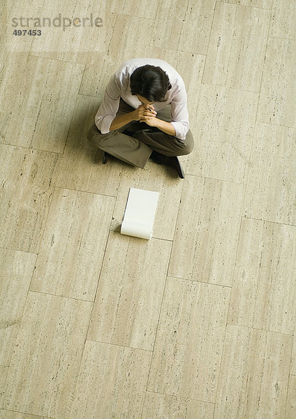 Mann auf dem Boden sitzend mit einem leeren Block aus Papier  hohe Blickwinkel