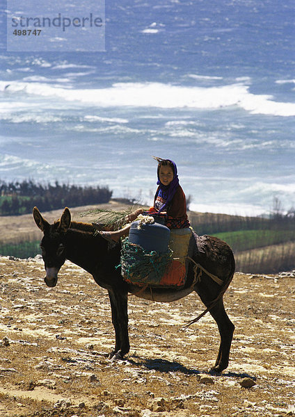Marokko  Mädchen auf Esel mit Meerblick