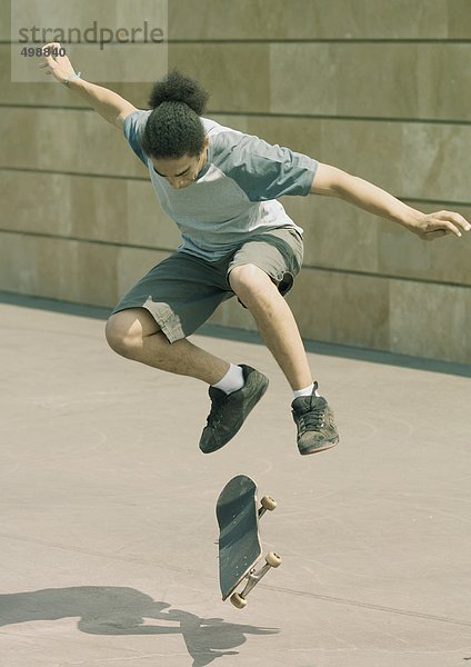 Junger Mann macht Trick auf dem Skateboard