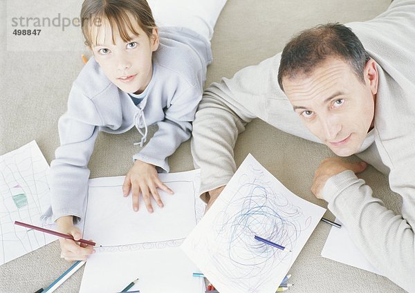 Mann und Tochter liegen auf dem Boden und zeichnen zusammen