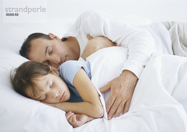 Mann neben Tochter im Bett liegend