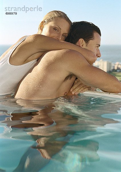 Frau umarmt Mann im Pool