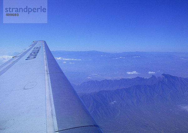 Flugzeugflügel beim Flug über Berge