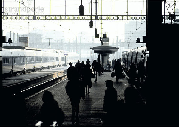 Menschen in Silhoutte auf überfülltem Bahnsteig