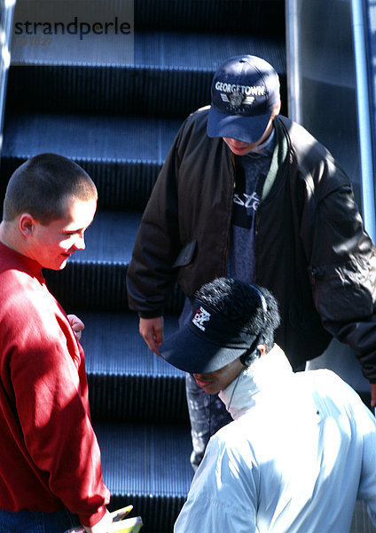 Junge Männer auf der Rolltreppe  Rückansicht.