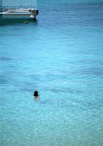 Schwimmende Person im Meer in der Nähe eines Motorbootes