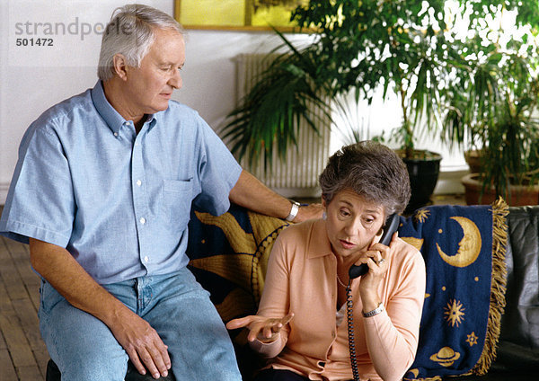 Ein Mann sitzt neben einer Frau am Telefon.