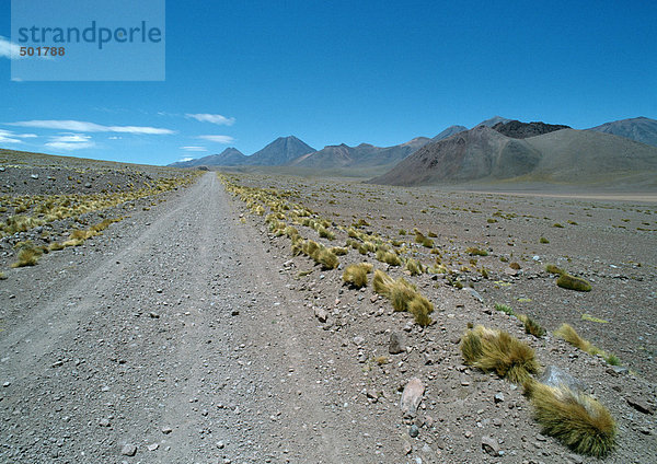 Chile  Antofagasta  Schotterstraße durch trockene Landschaft  Berge im Hintergrund