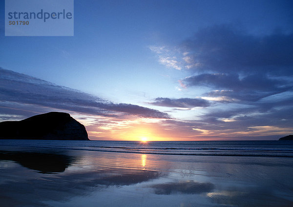 Neuseeland  Mahia Beach  Sonnenuntergang mit Klippe im Hintergrund.