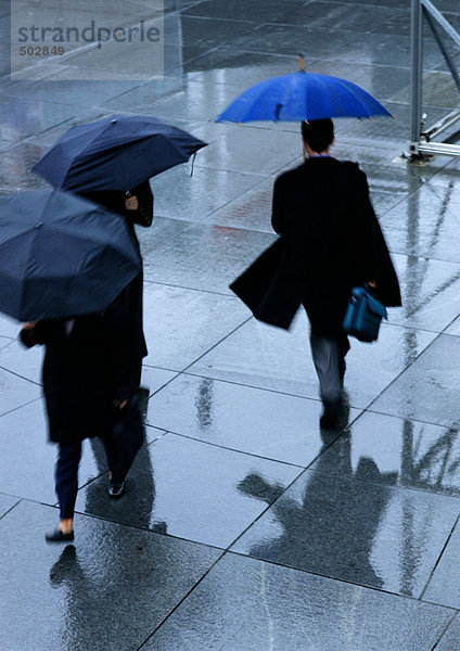 Drei Personen halten Regenschirme in der Straße  hohe Blickwinkel