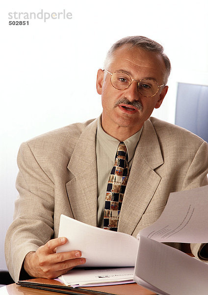 Mann am Schreibtisch sitzend  Dokument haltend