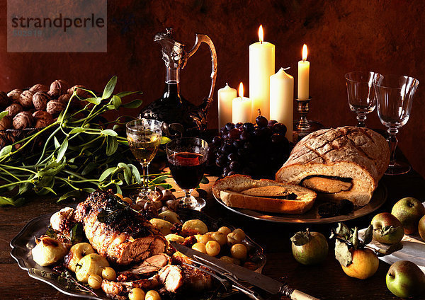 Gerichte aus Fleisch  Obst und Gemüse  mit Weinkaraffe und Kerzen im Hintergrund
