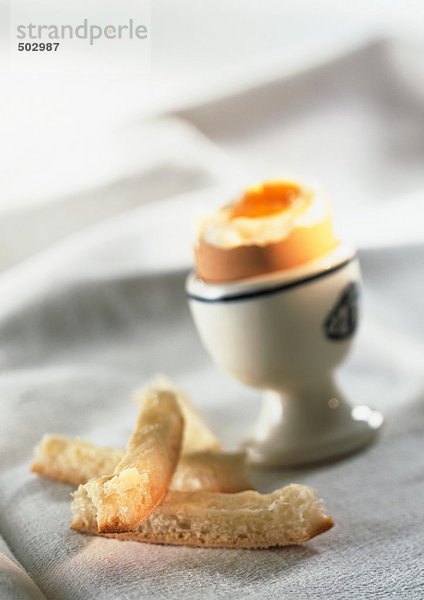 Weichgekochtes Ei im Eierbecher  verschwommen  mit Brotkruste