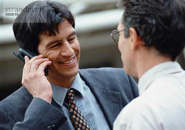 Zwei Geschäftsleute  einer hält ein Handy  lächelnd