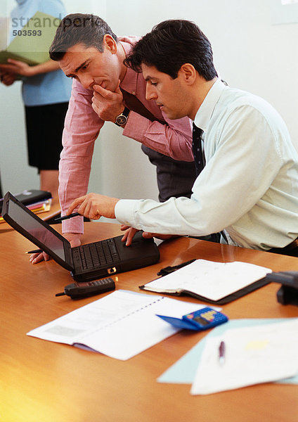 Zwei Geschäftsleute betrachten Laptop-Computer
