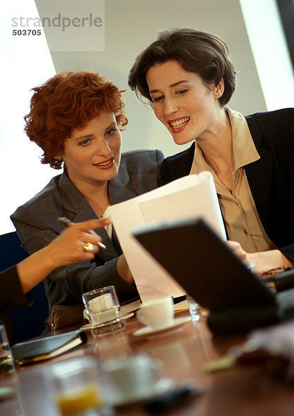 Zwei Geschäftsfrauen sitzen und schauen sich das Dokument an.