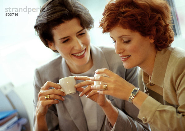 Zwei Geschäftsfrauen Seite an Seite  die Kaffeetassen halten