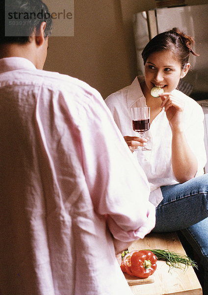 Frau isst und hält Glas  Rückansicht des Mannes im Vordergrund  verwischt