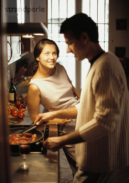Frau sieht den Mann beim Kochen an