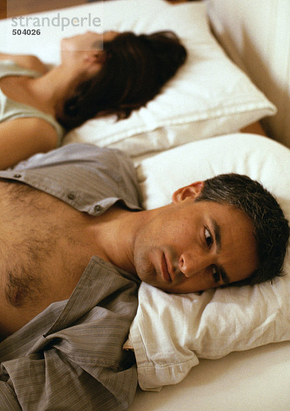 Mann und Frau liegen im Bett  Köpfe auf Kissen  gegensinnig  Kopf und Schultern